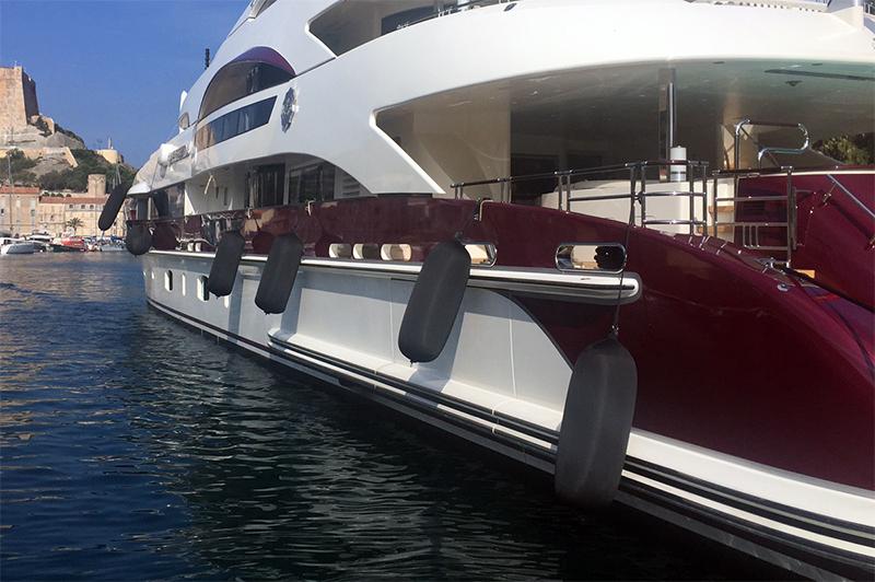 Superyacht berthed alongside with cylindrical fenders deployed along the length of the hull