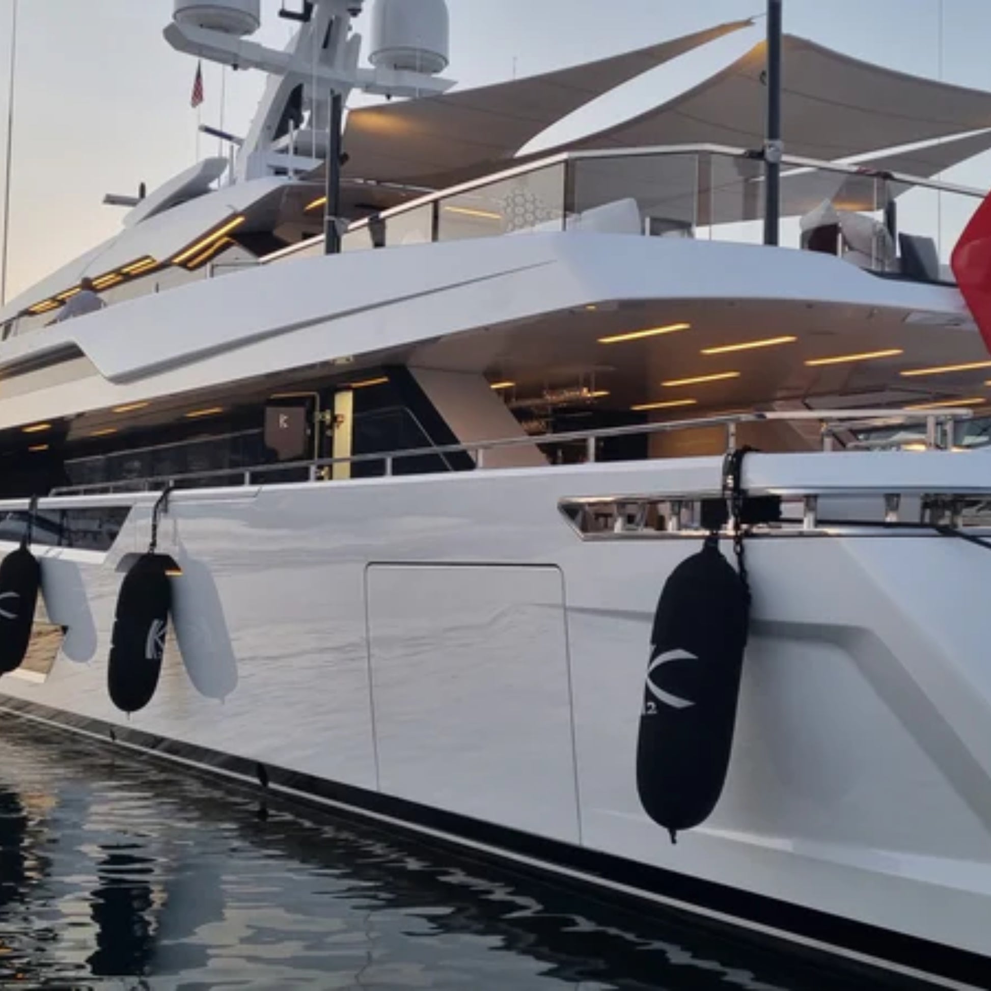 Fendertex textile fenders in black hanging along the hull of a large superyacht moored at dusk